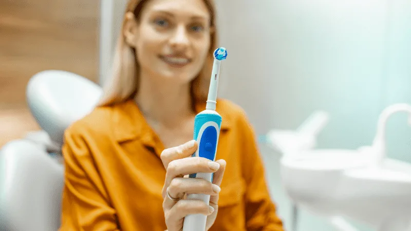 lady with electric toothbrush at dentist office